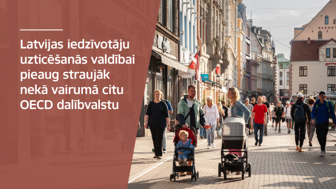 Cilvēki, kas staigā pa ielu. Uzraksts "Latvijas iedzīvotāju uzticēšanās valdībai pieaug straujāk nekā vairumā citu OECD dalībvalstu"